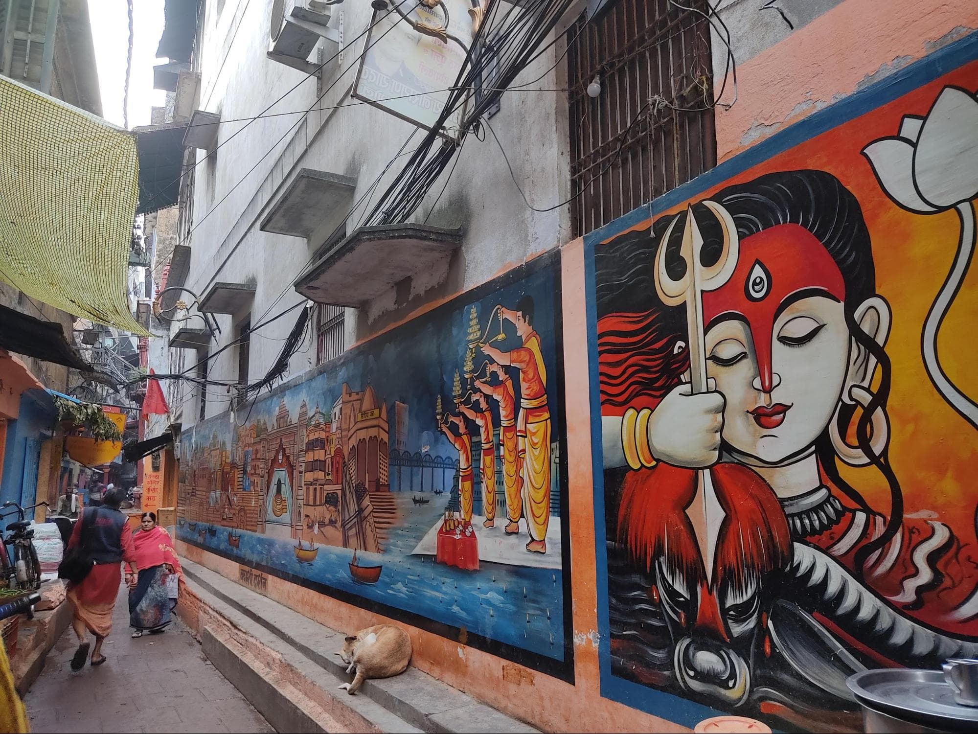 Narrow alley of Banaras which has houses, small shops and walls with paintings of Lord Shiva